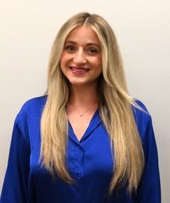 A woman in a black shirt is standing in front of a tree.