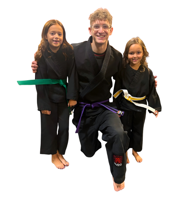 Man pointing, smiling, wearing black hoodie; arm tattoo visible.