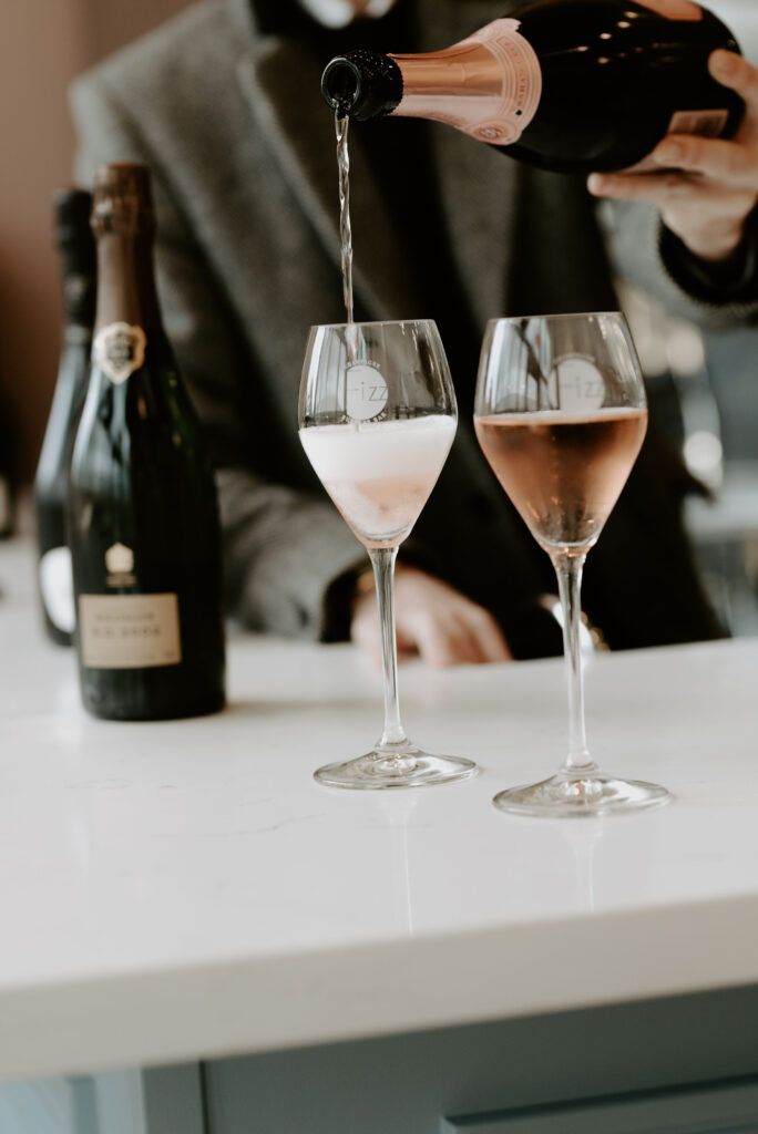 A bottle of champagne being poured into Fizz champagne glasses.