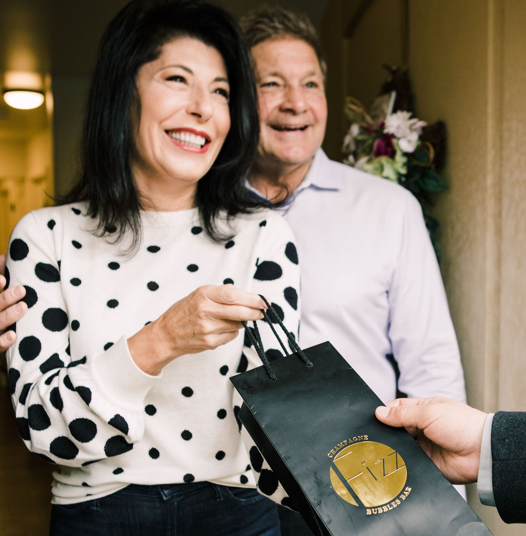 A couple receiving a champagne bottle as a gift.