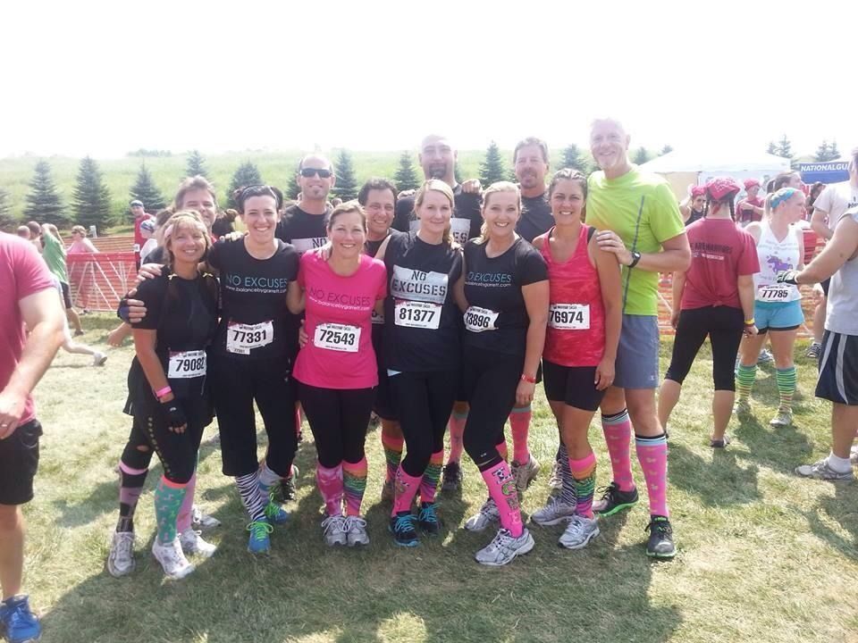 Group of runners in matching socks and shirts pose after a race outdoors.