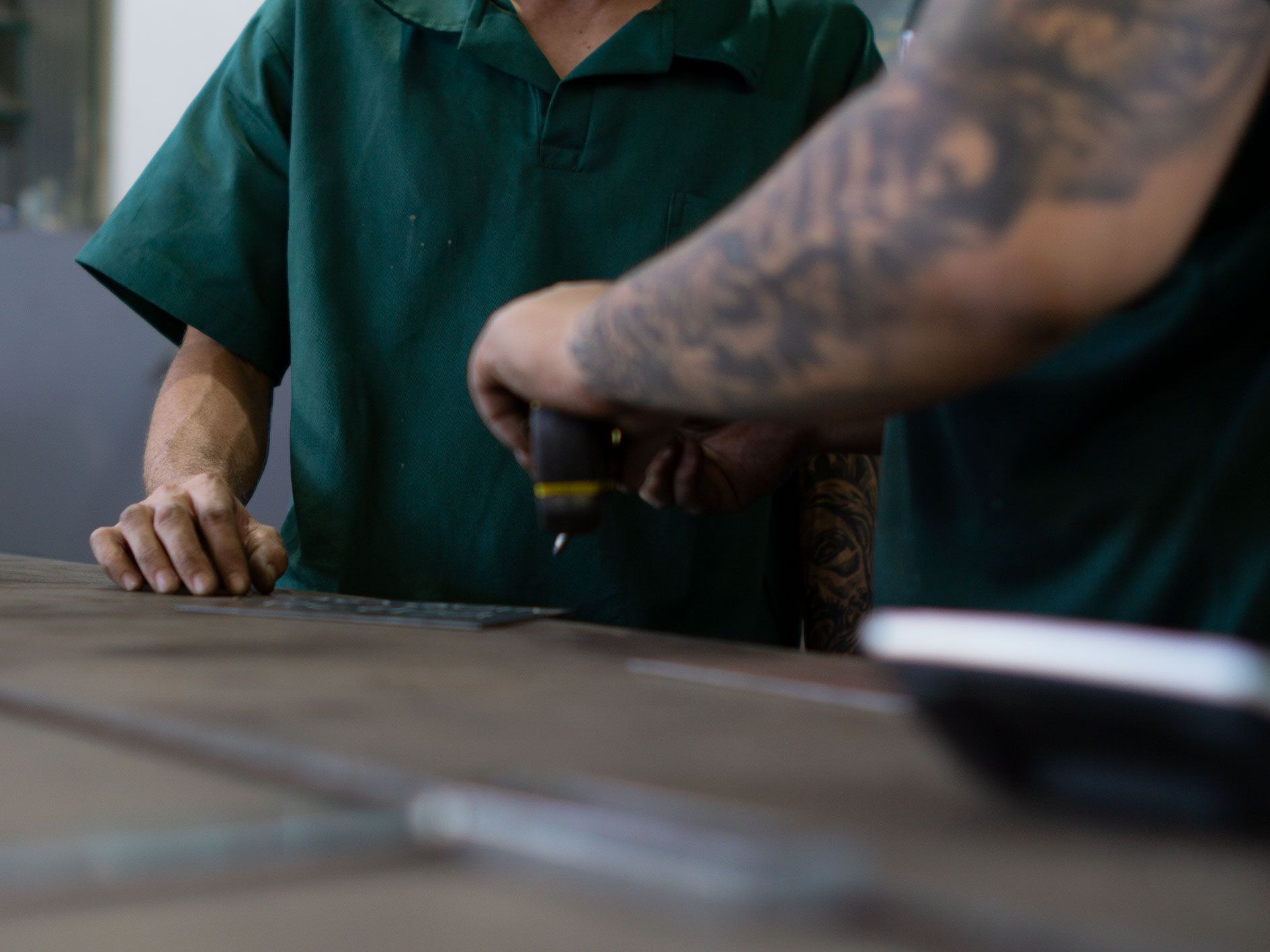 A man with a tattoo on his arm is working on a piece of wood.