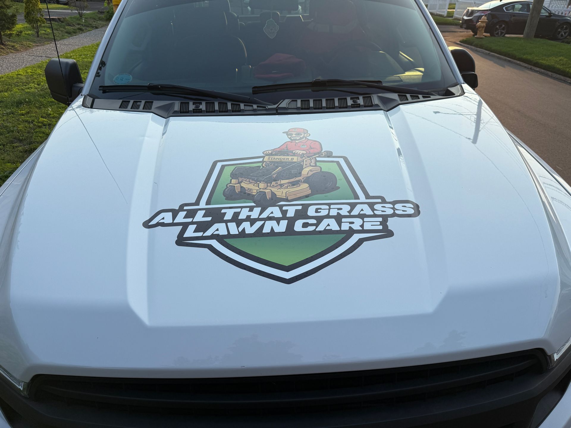 A white truck with a sticker on the hood that says all that grass lawn care