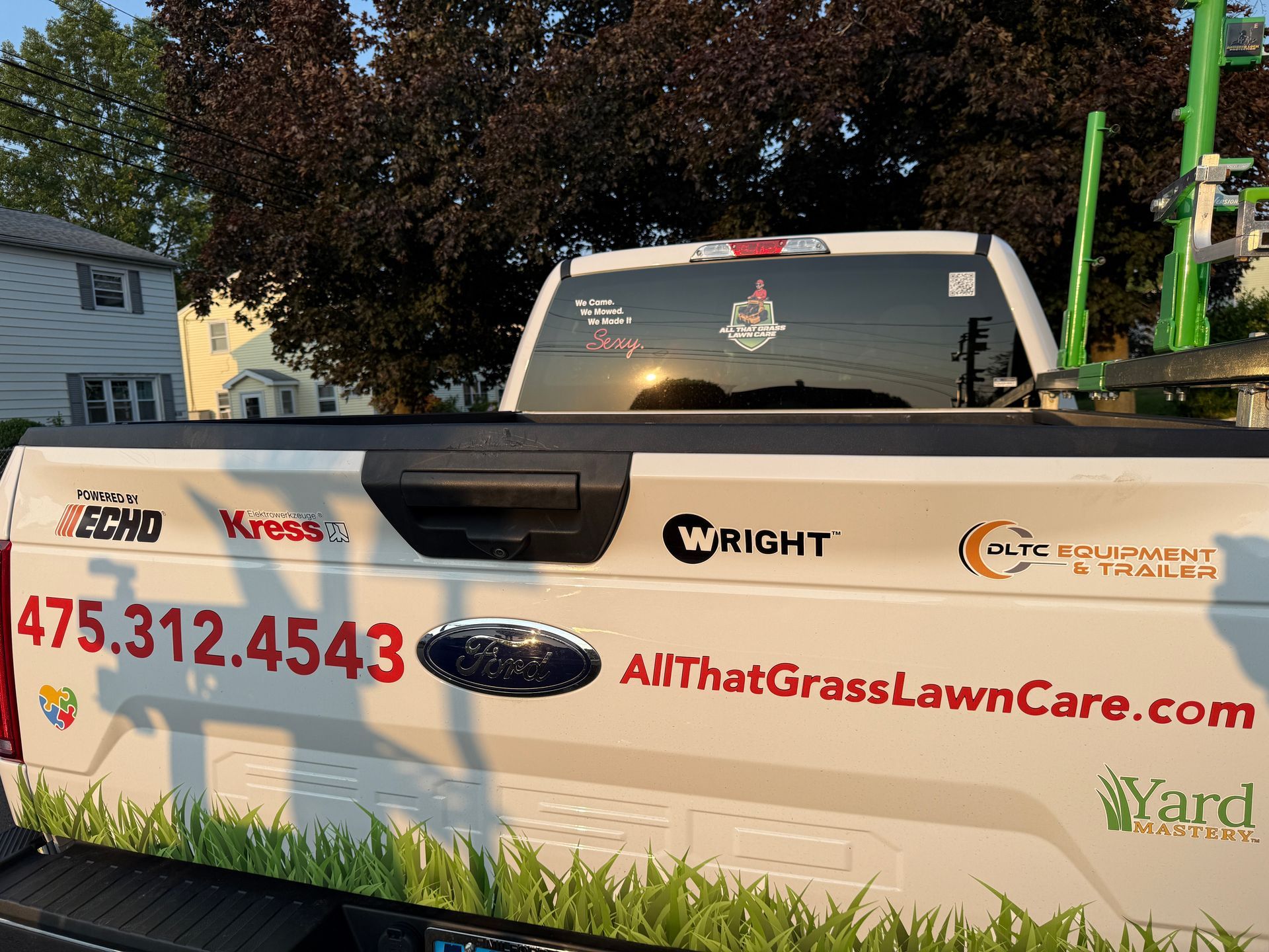 A white truck with a lawn care company written on it