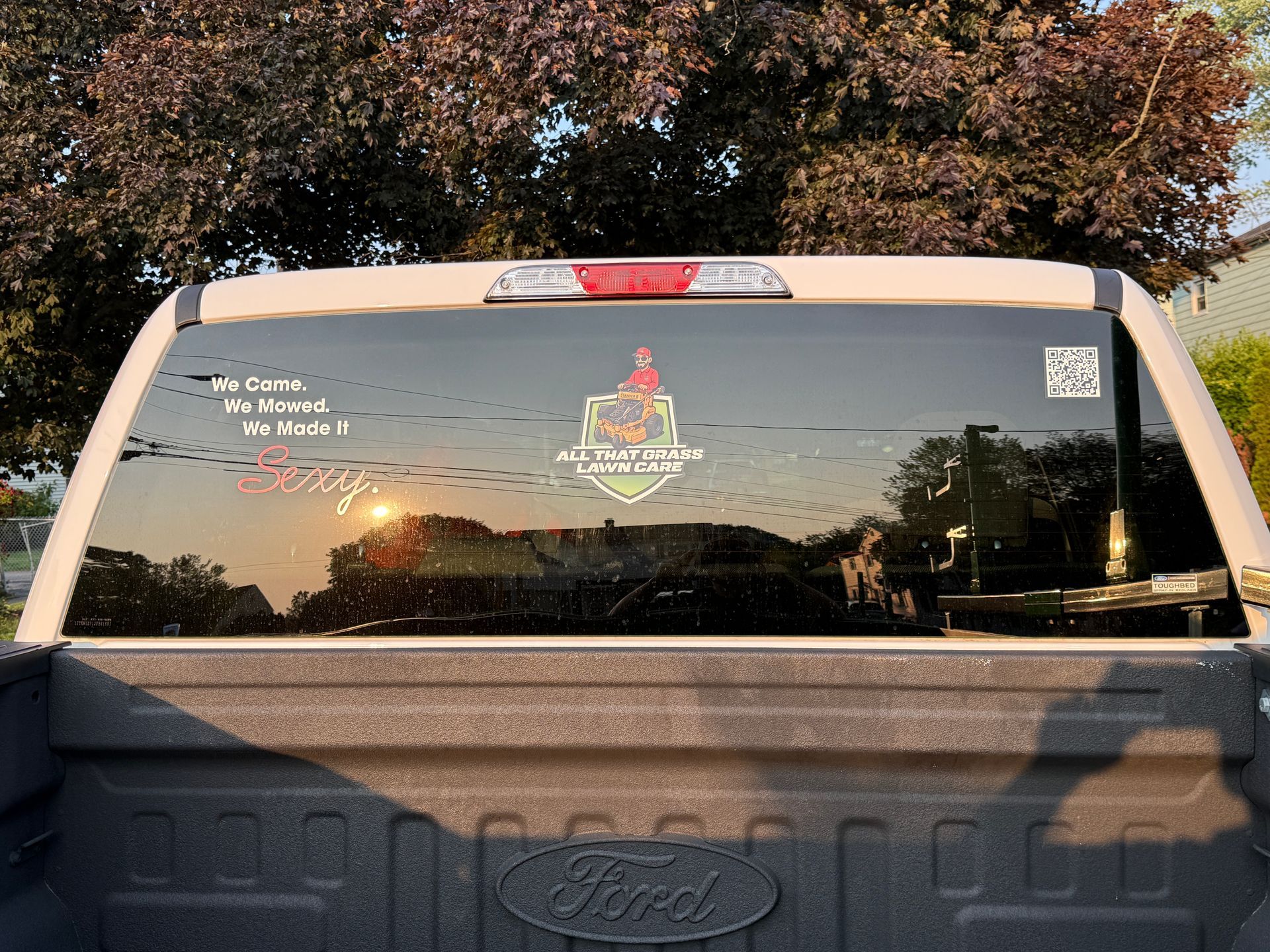 A white ford truck with a sticker on the back window.
