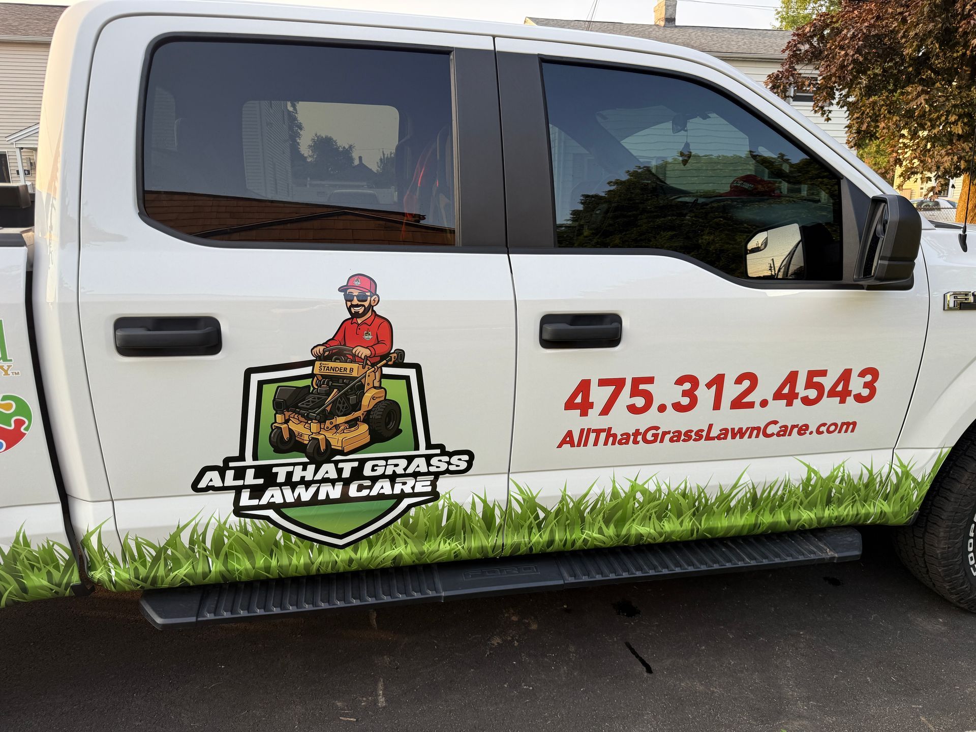 A white truck with all that grass lawn care written on the side
