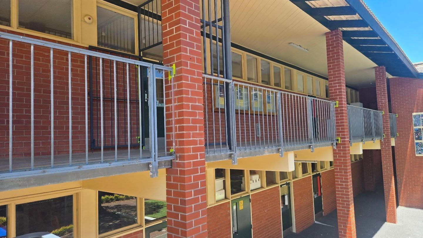 A brick building with a balcony and a metal railing.