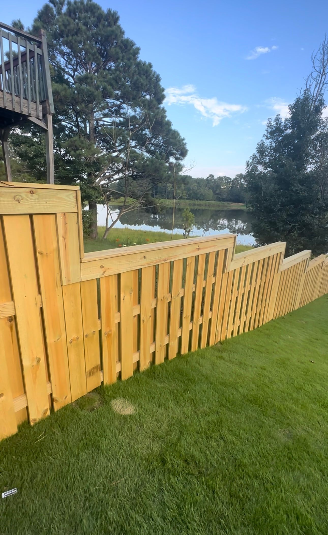 Nice new wooden fence around house. Wooden white fence with green lawn. Street photo, nobody, selective focus.