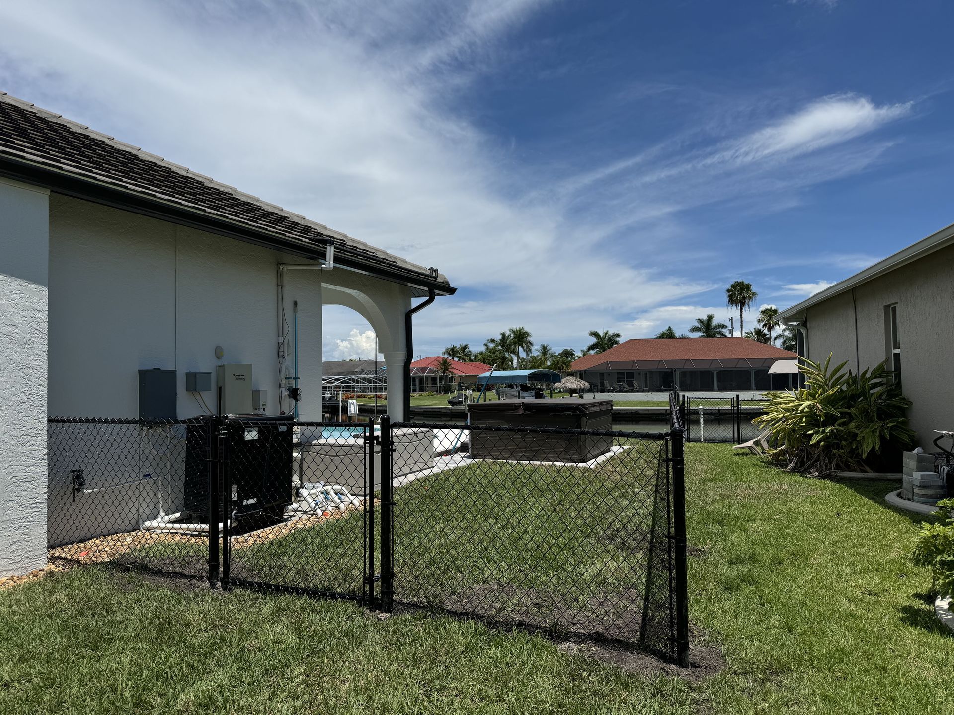 A black chain link fence is in the backyard of a house.