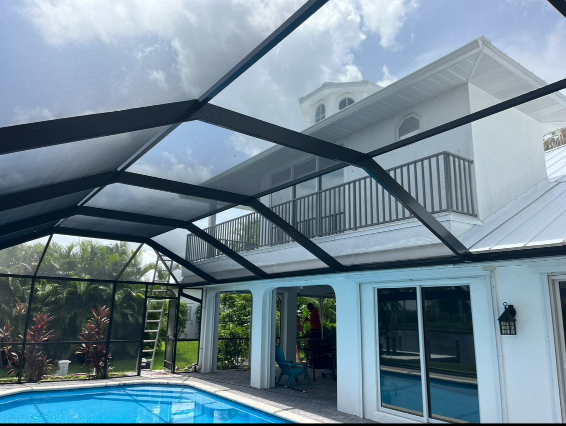 A swimming pool with a gazebo and chairs and an umbrella.