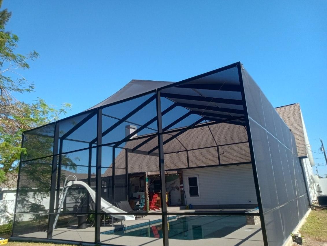 A screened in pool area with a house in the background.