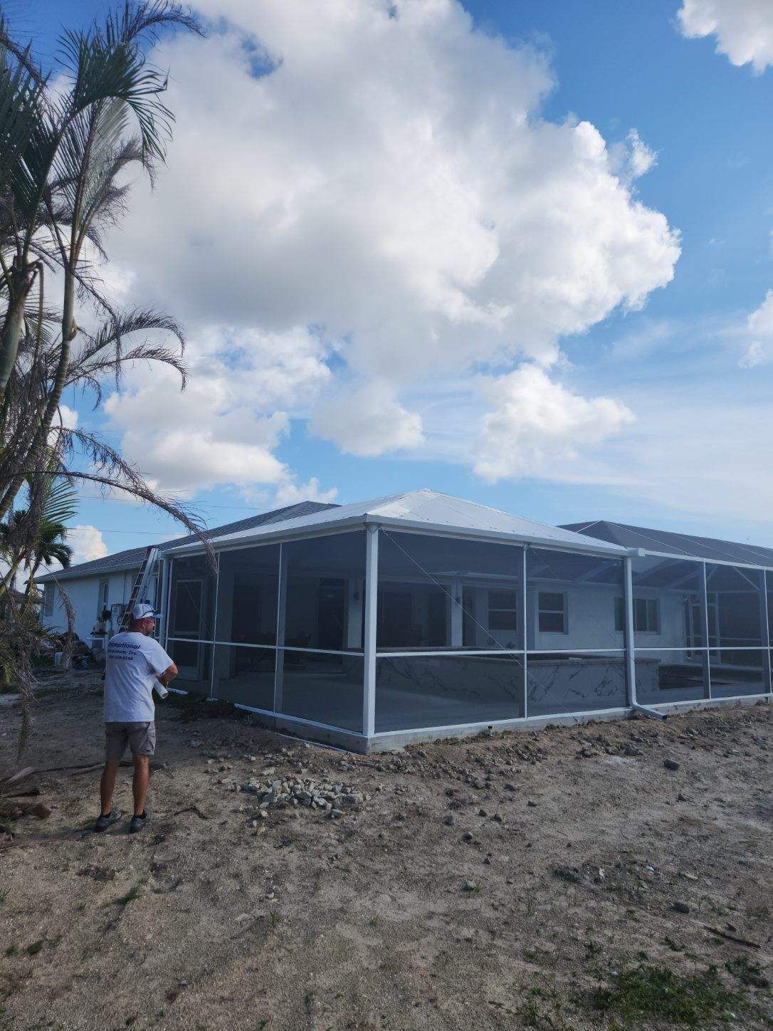 A man is standing in front of a house with a screened in porch.