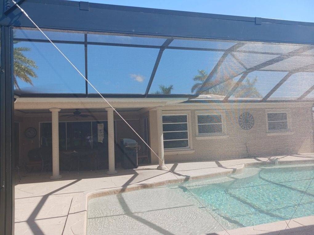 A screened in porch with a swimming pool in the background.