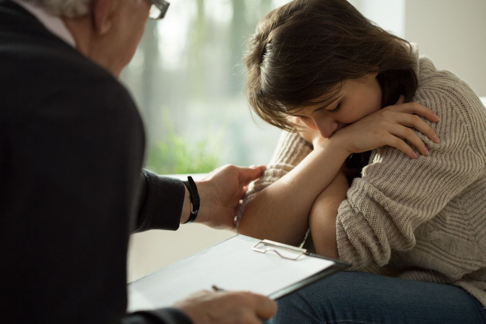 A Sad Woman Covering Her Face While A Man Writes On A Clipboard — Naturopath Australia In Mermaid Beach, QLD