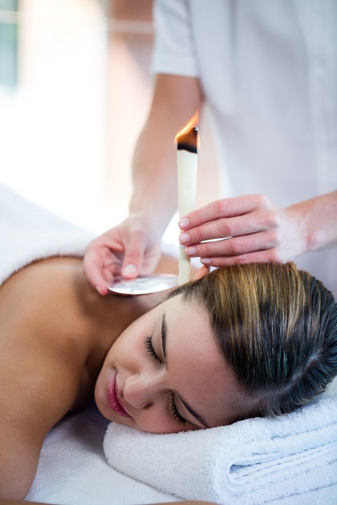A Woman Is Getting A Massage With A Candle In Her Ear — Naturopath Australia In Mermaid Beach, QLD