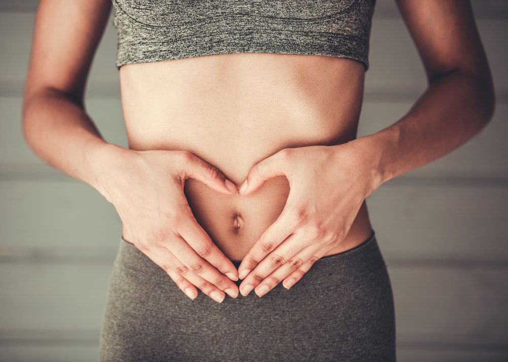 A Woman Is Making A Heart Shape With Her Hands On Her Belly — Naturopath Australia In Mermaid Beach, QLD