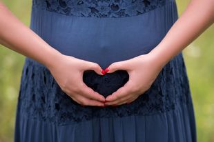 A Woman In A Blue Dress Is Making A Heart Shape With Her Hands Above Her Stomach — Naturopath Australia In Mermaid Beach, QLD