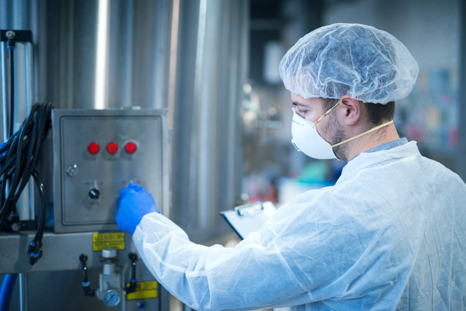 Man in protective gear operating machinery, possibly in a factory setting.