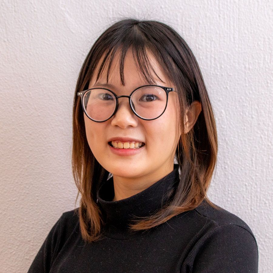 A young woman wearing glasses and a black turtleneck is smiling for the camera.