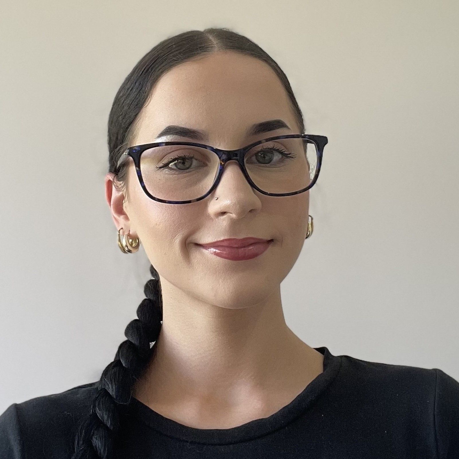 A woman with rainbow hair is smiling and wearing a black shirt.