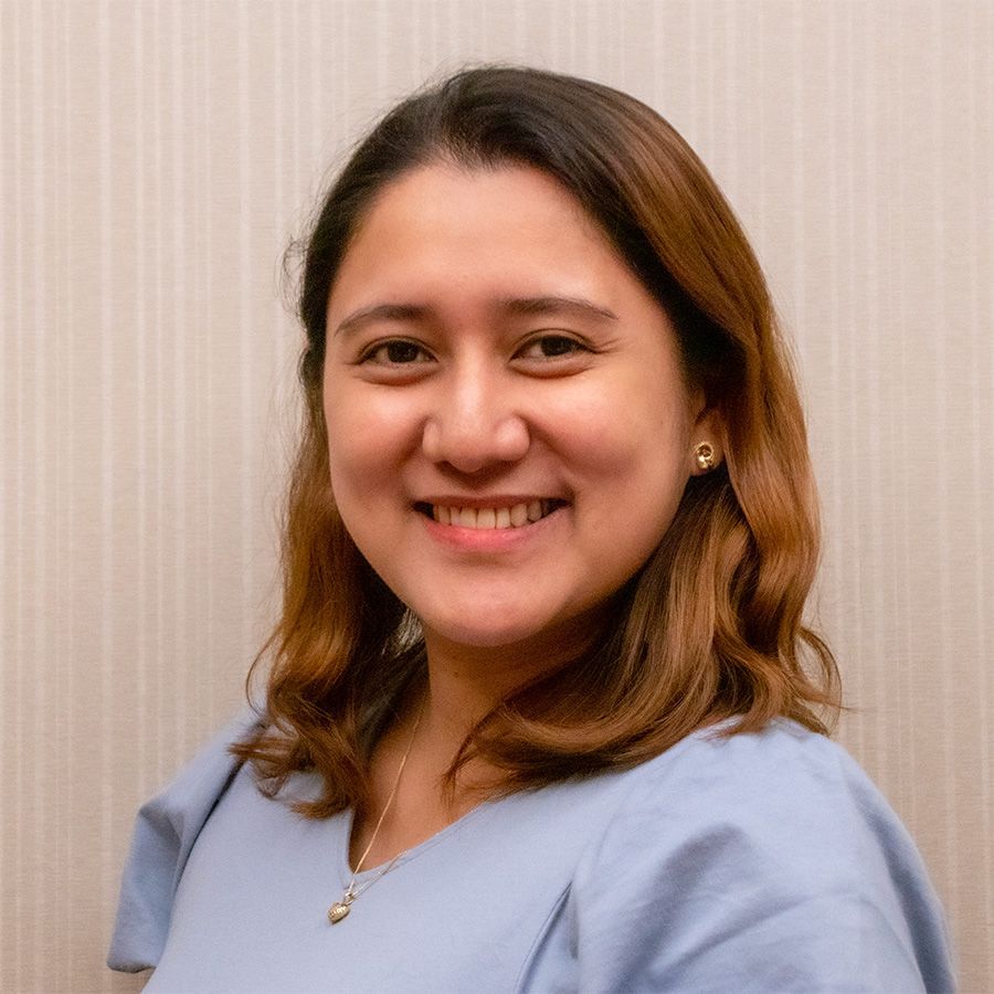 A woman in a blue shirt is smiling for the camera.