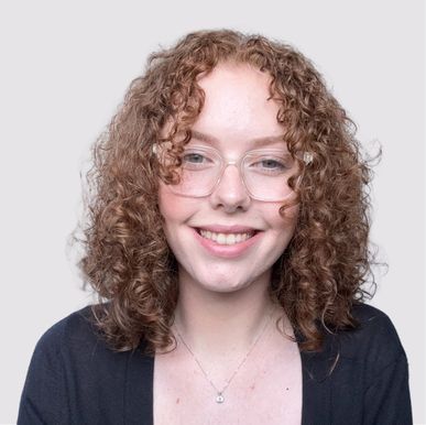 A woman with red hair is smiling and wearing a black shirt