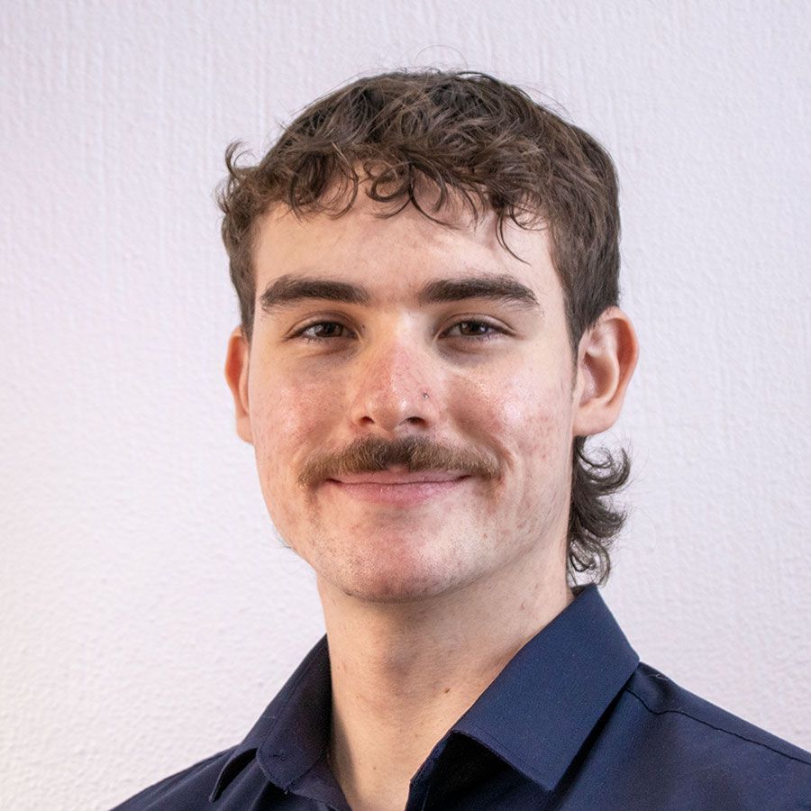 A man wearing glasses and a suit is smiling for the camera.