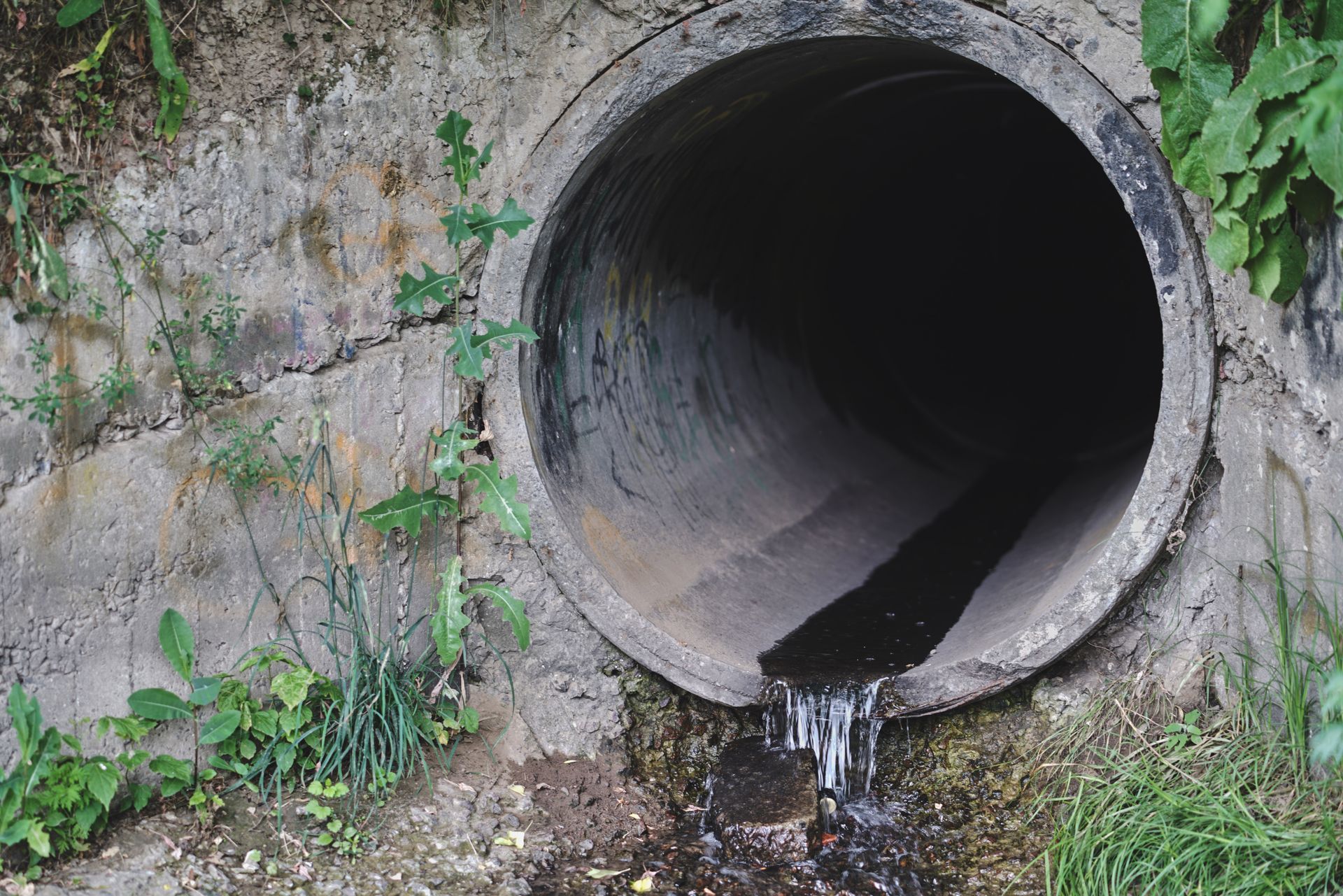 A large concrete pipe with water coming out of it.