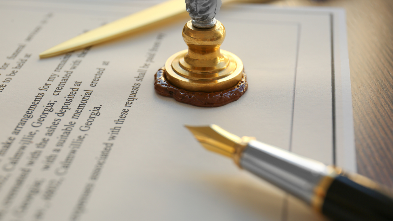 A golden wax seal stamp on a document next to a fountain pen and a letter opener.