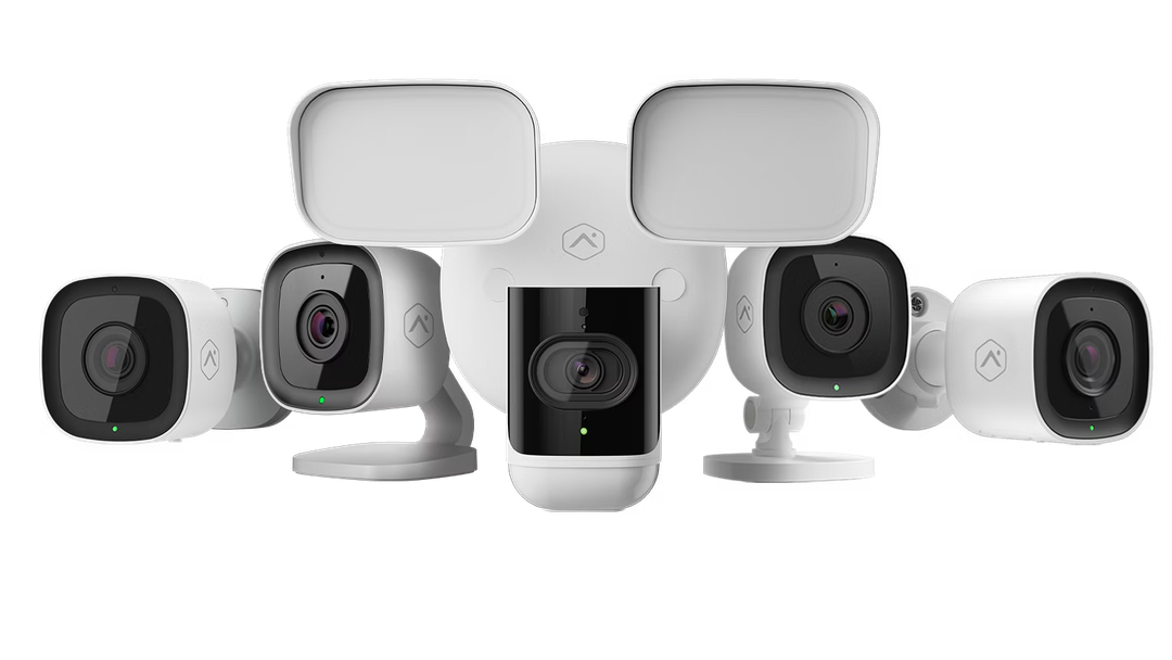 Four gray home security cameras displayed in a row on a white background