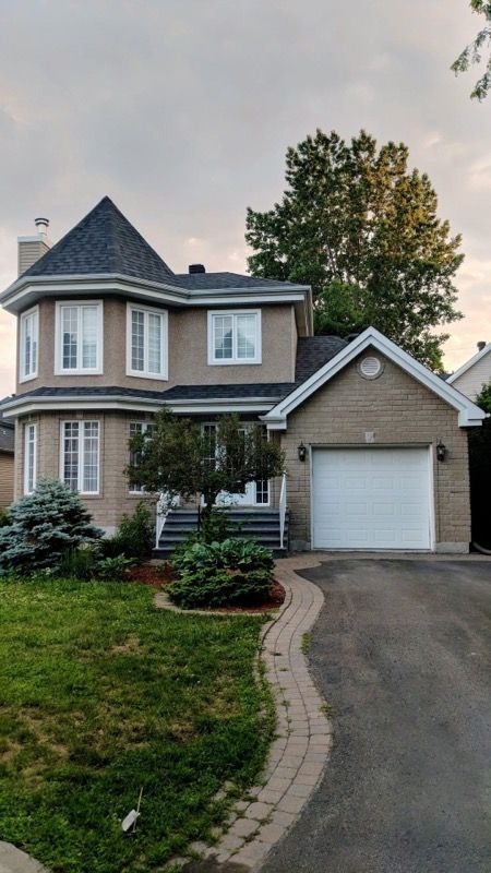 Une grande maison avec un garage et une allée devant.