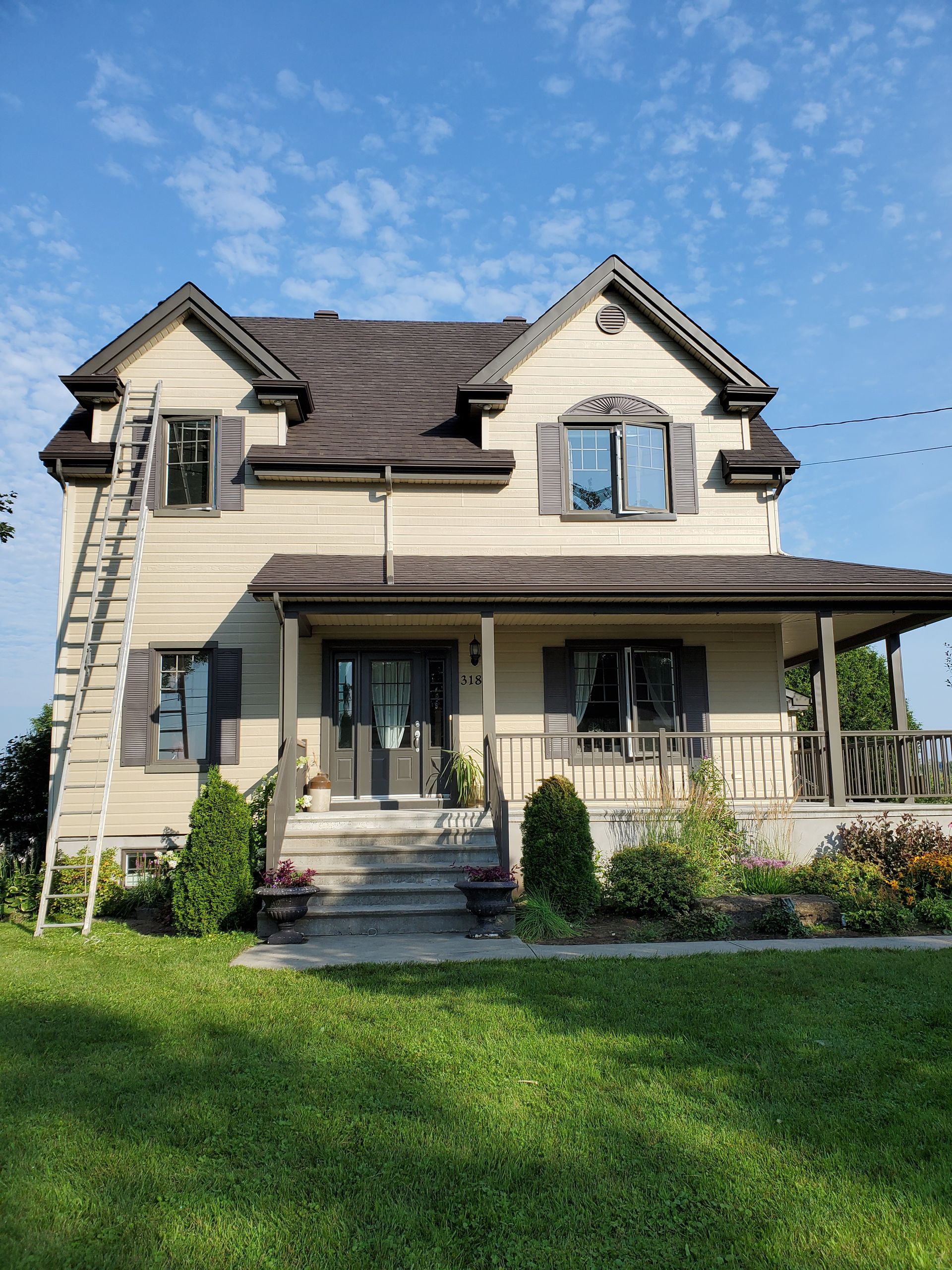 Une grande maison avec un porche et une échelle sur le côté.