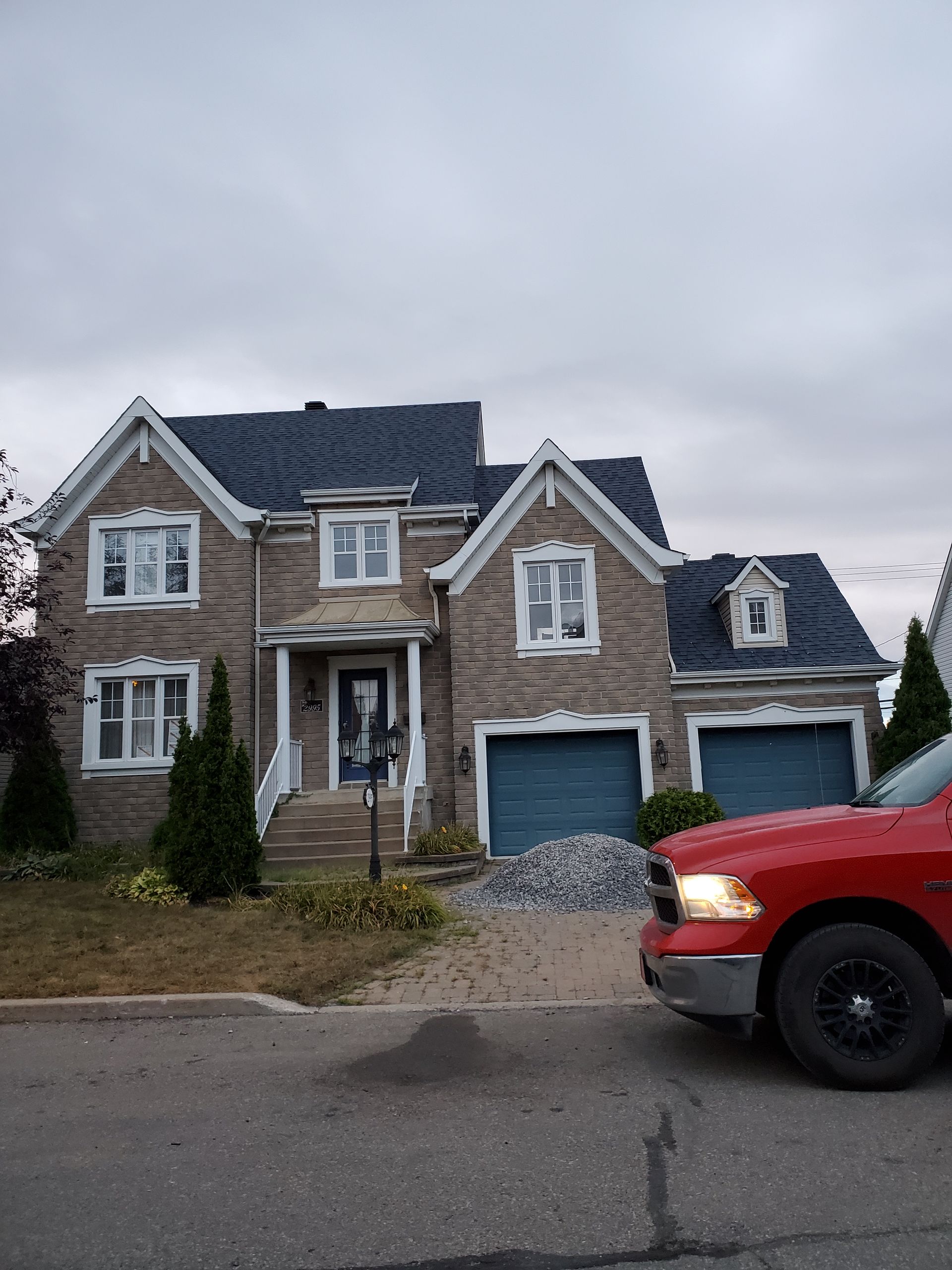 Un camion rouge est garé devant une grande maison en briques