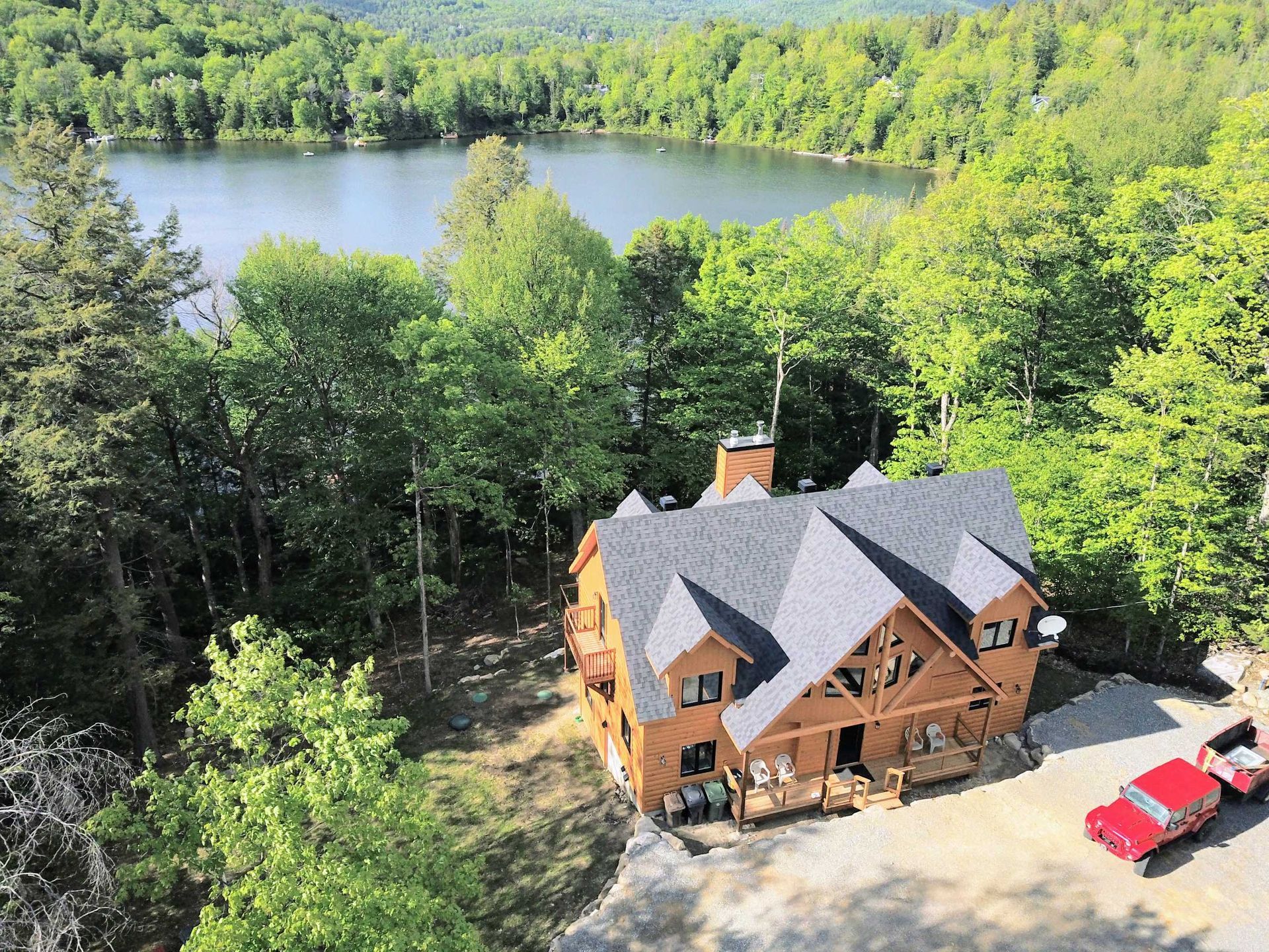 Une vue aérienne d'une maison entourée d'arbres et d'un lac.