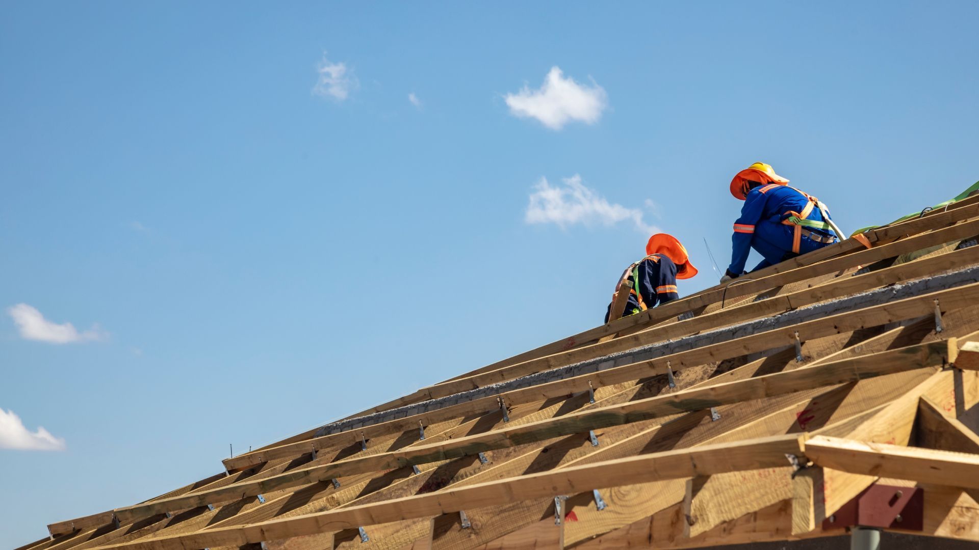 Two construction workers are working on the roof of a building.
