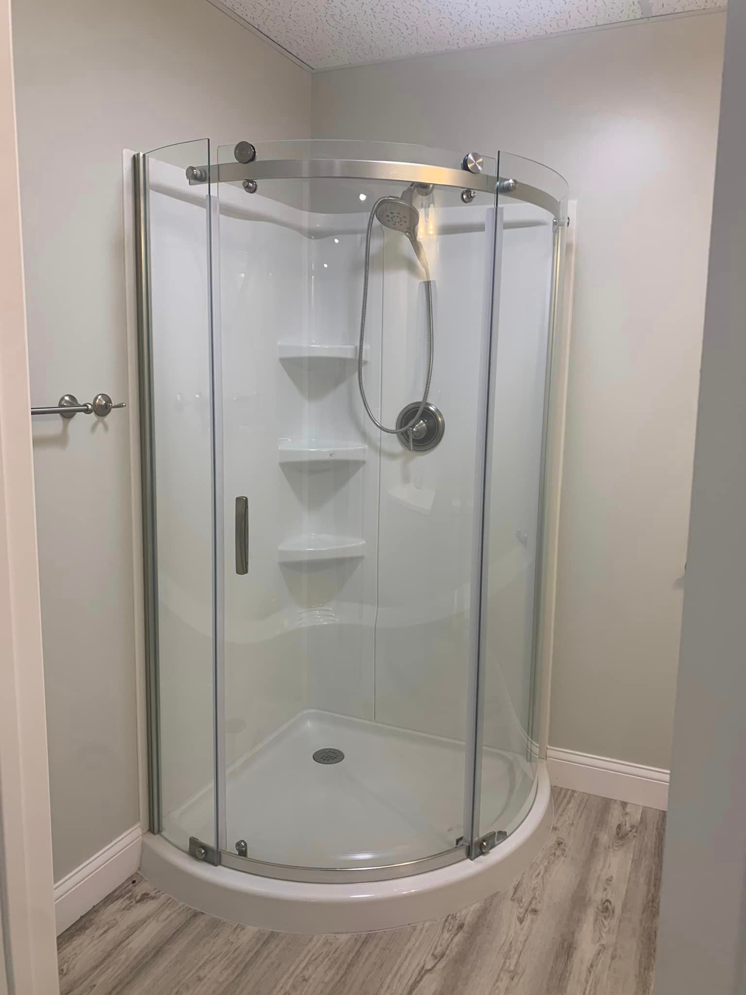 A bathroom with a curved shower stall and a shower head.