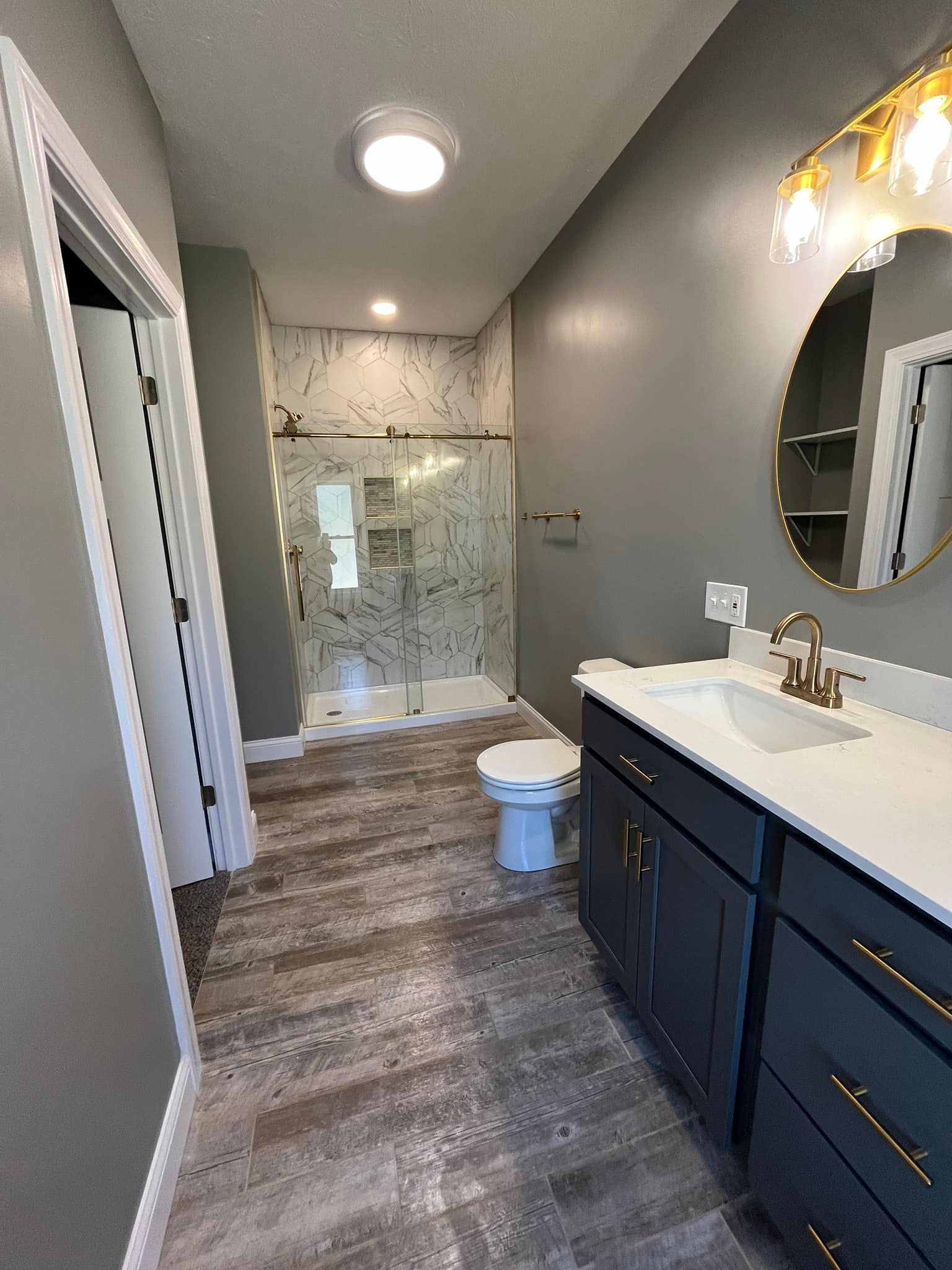A bathroom with a sink , toilet , shower and mirror.