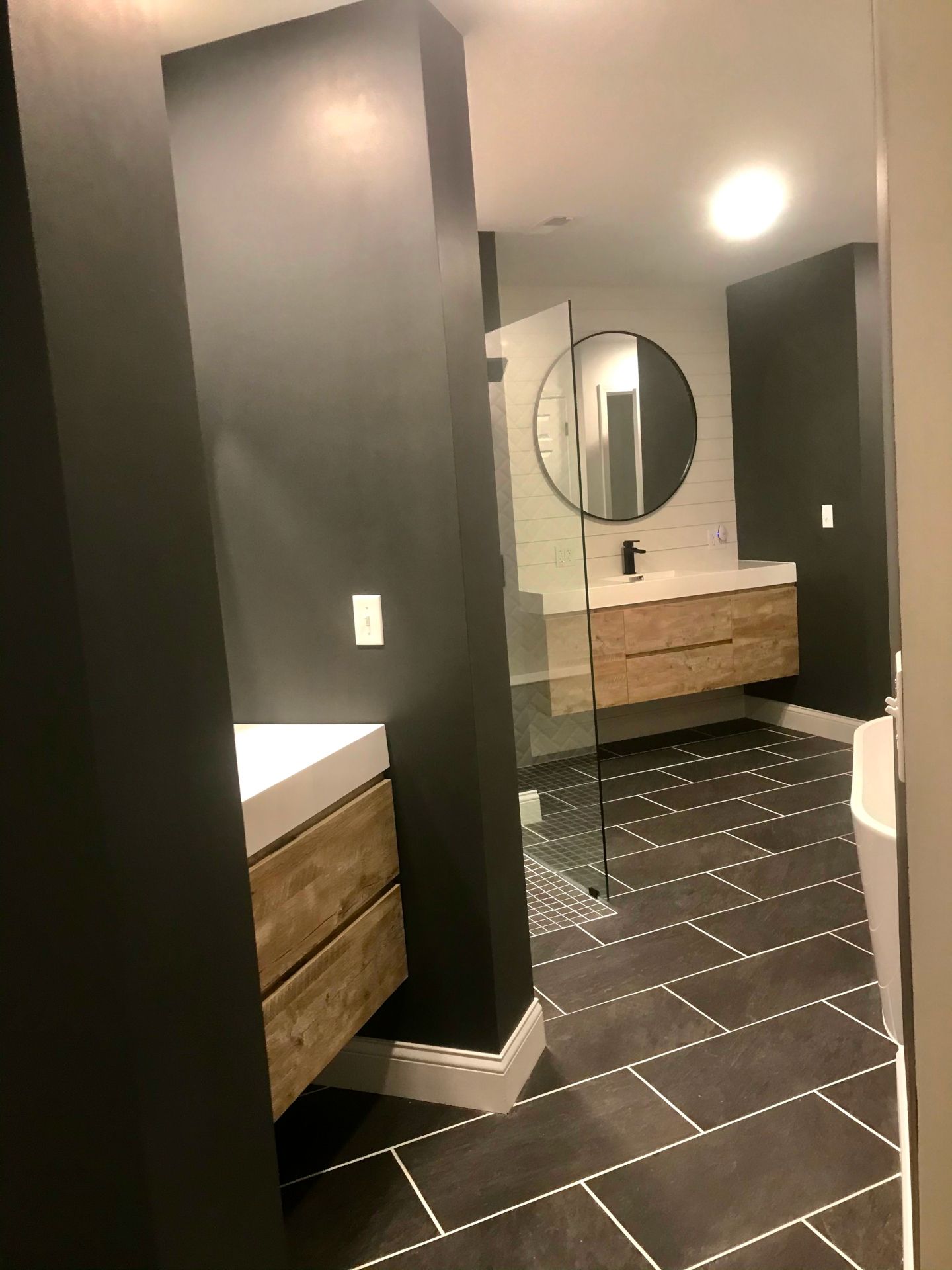 A bathroom with two sinks and a round mirror