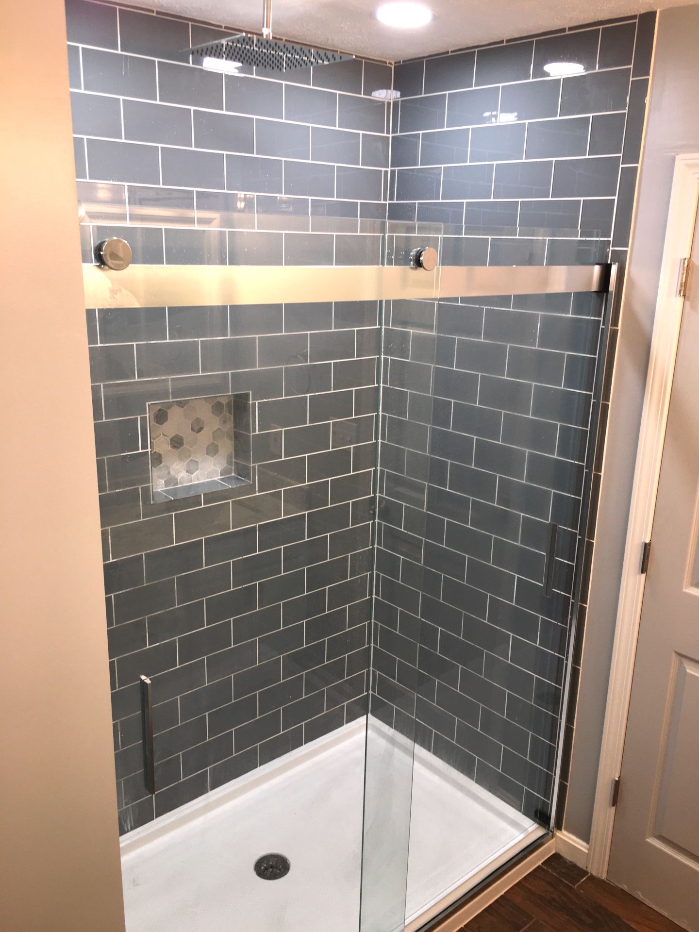 A shower stall with a sliding glass door and a shower head.