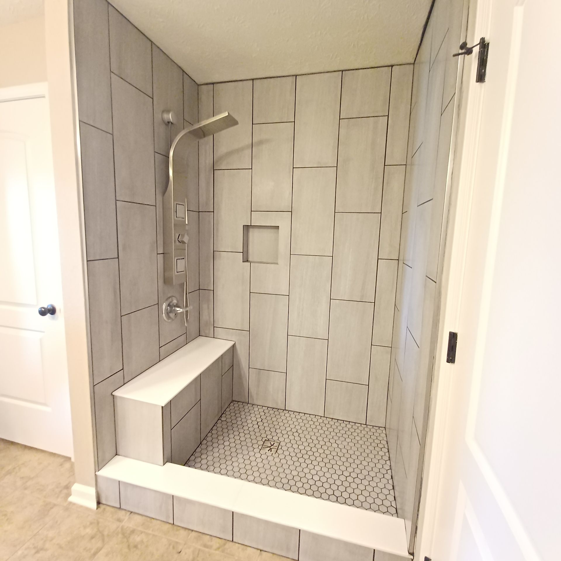 A bathroom with a walk in shower and a bench.