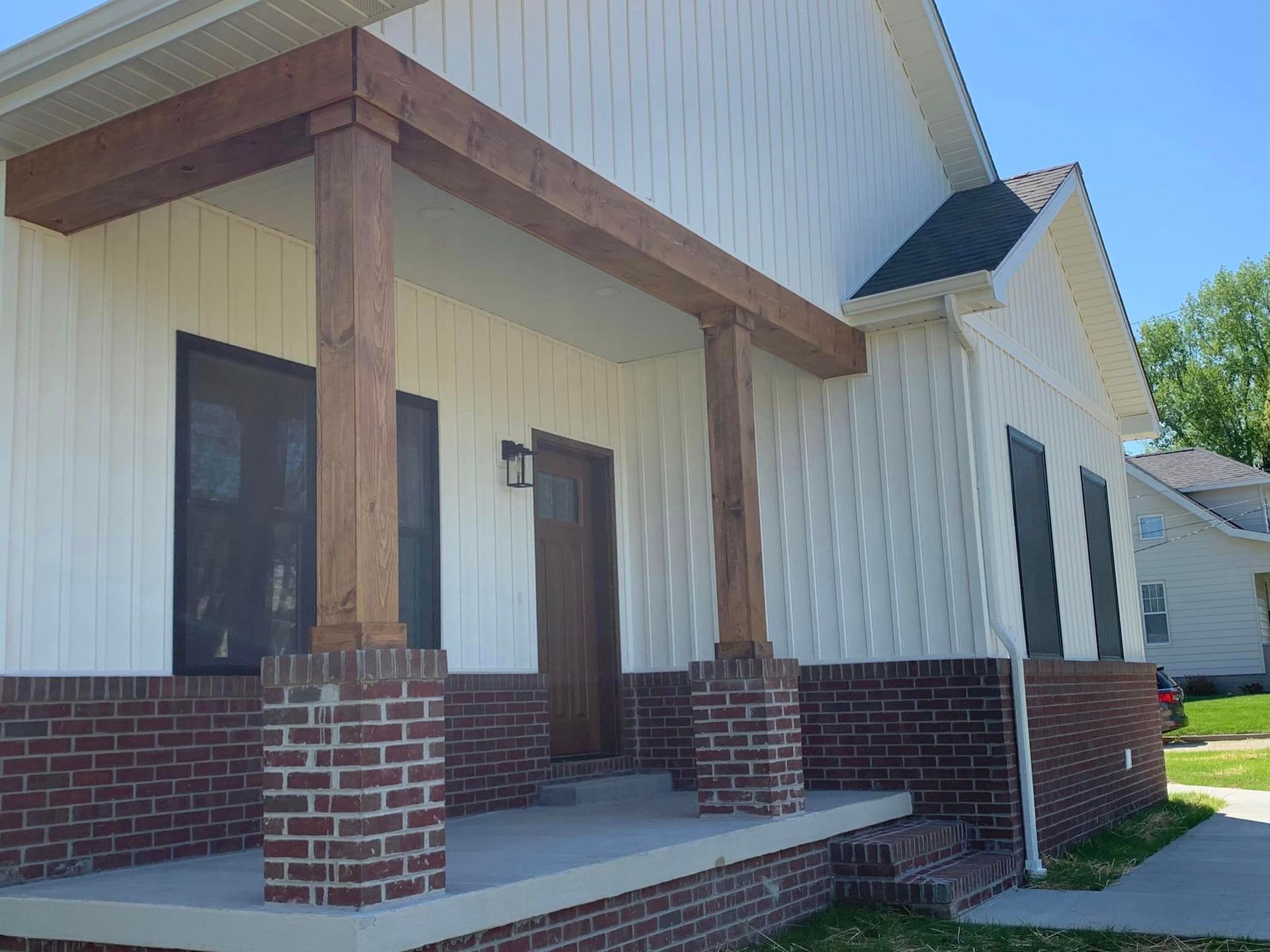 A white house with a brick porch and wooden beams