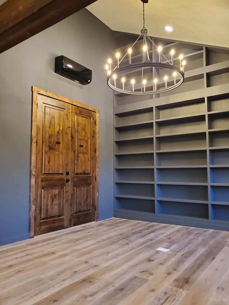 An empty room with a chandelier hanging from the ceiling and shelves.