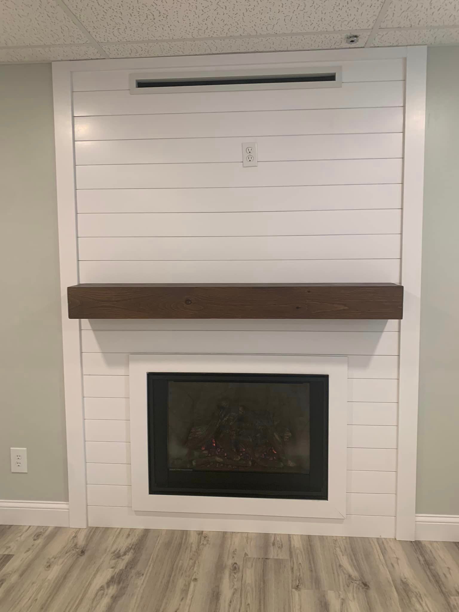 A fireplace in a basement with a wooden mantle.