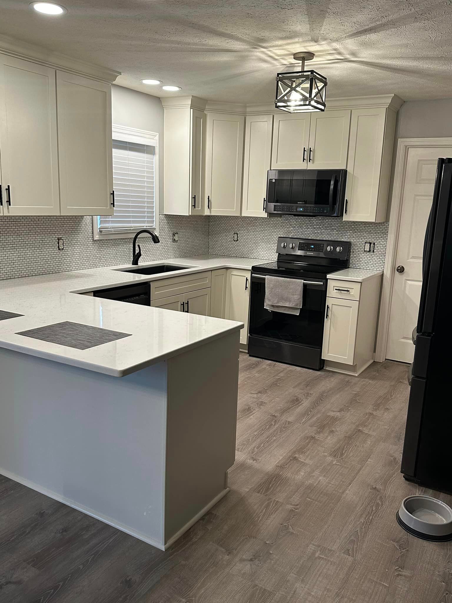A kitchen with white cabinets , black appliances , and a large island.