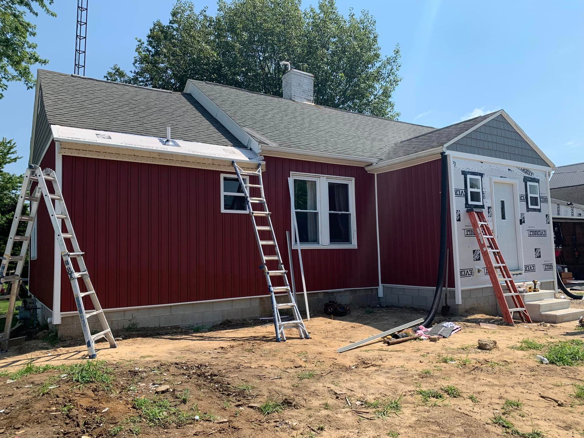 A house with red siding and a ladder in front of it.