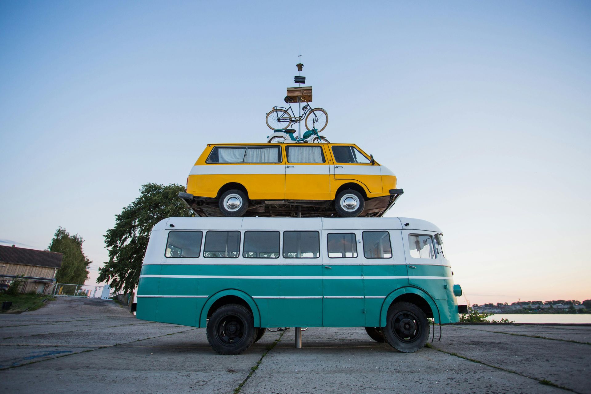 A yellow van sits on top of a green bus