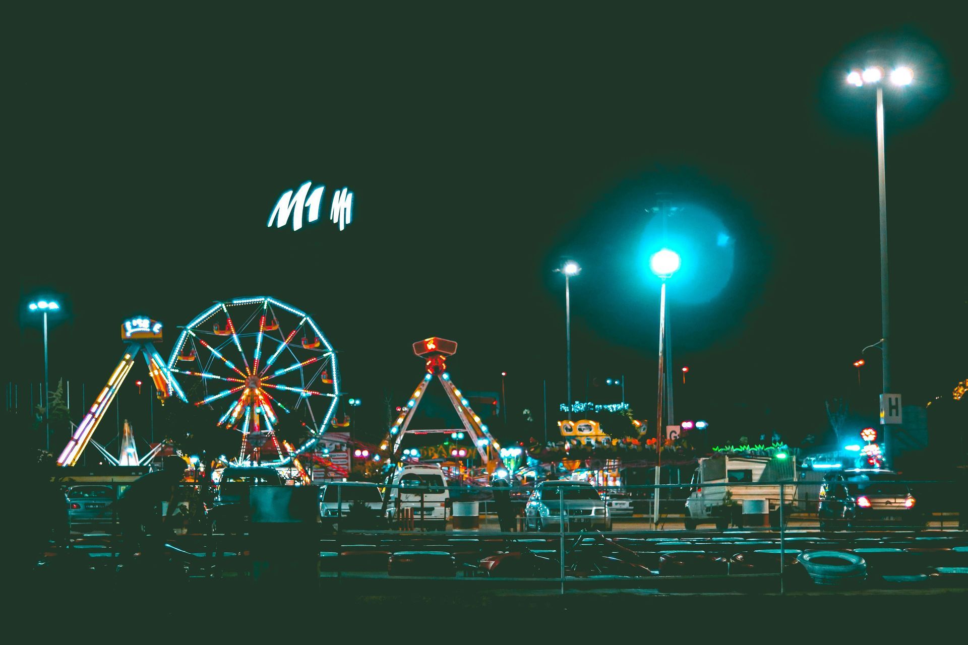 A carnival at night with a ferris wheel in the foreground