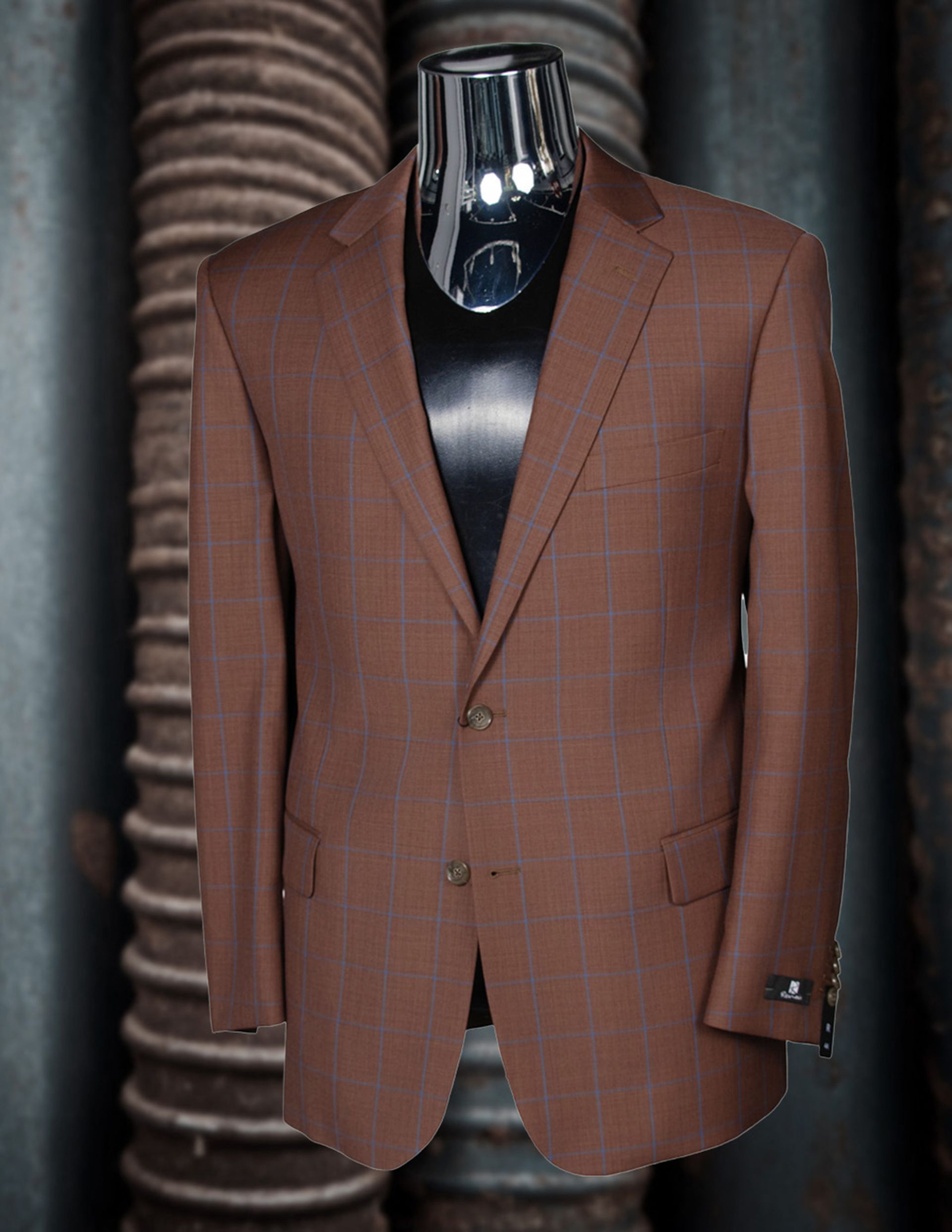 Brown suit jacket on a black mannequin, against a textured background.