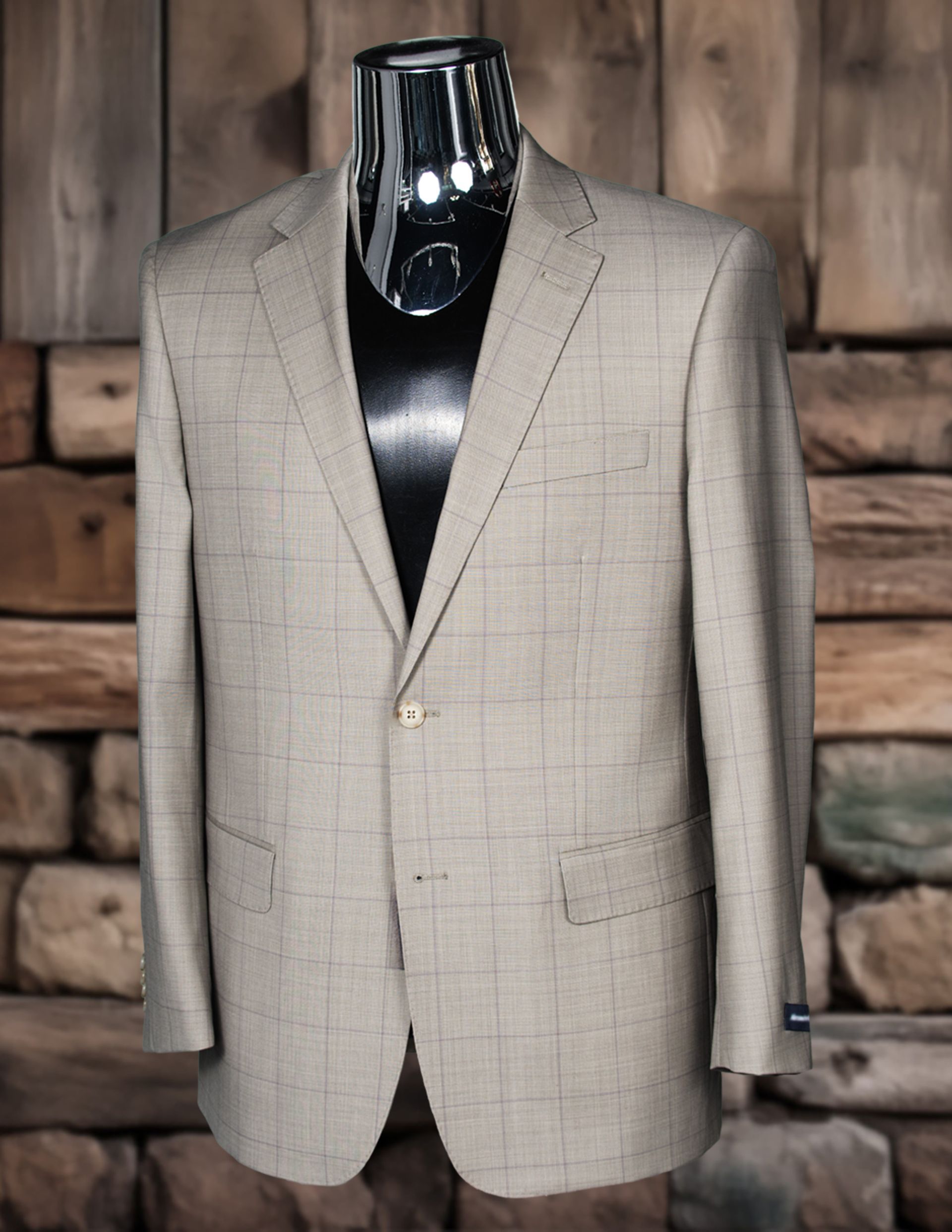 Beige and gray plaid blazer on a mannequin in front of a stone wall.