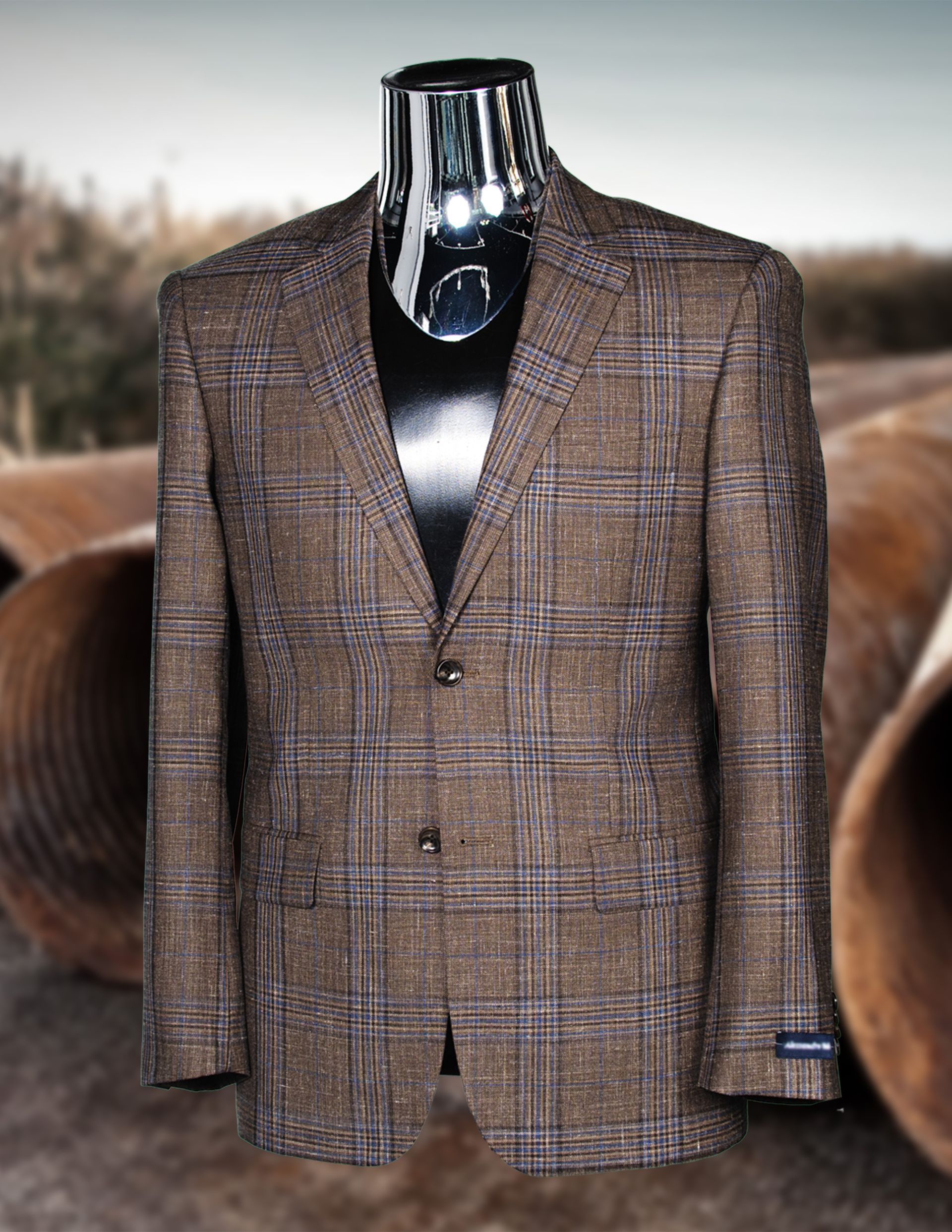 Brown plaid blazer on a headless mannequin, set against blurred industrial backdrop.
